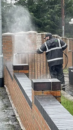 Tidy Jet Washing cleaning exterior brickwork beside a driveway.